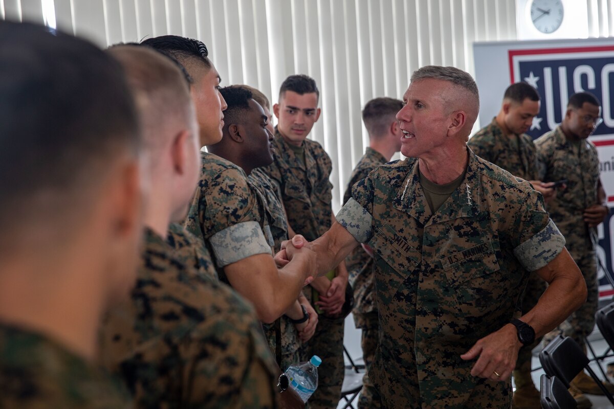 A man in a military uniform shakes the hand of another man in a military uniform.