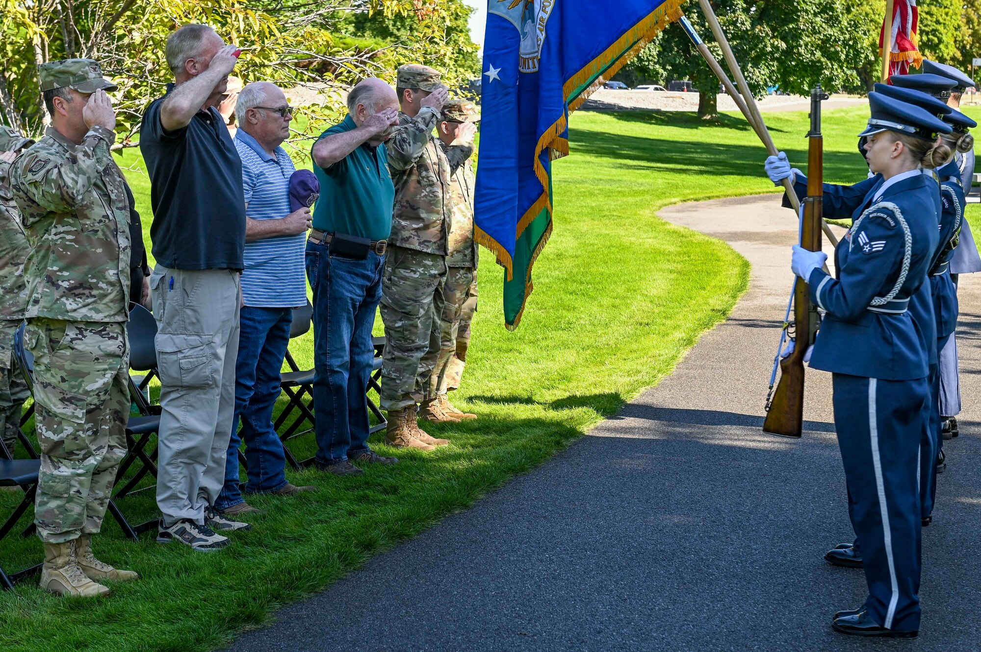 Attendees of the  Outcome 54 and 55 commemoration ceremony render honors to the American flag.