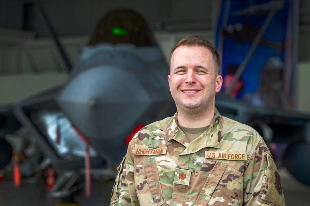 Maj. Stephen Brightman, Bilateral Affairs Officer, stands in front of an F-22 Raptor.