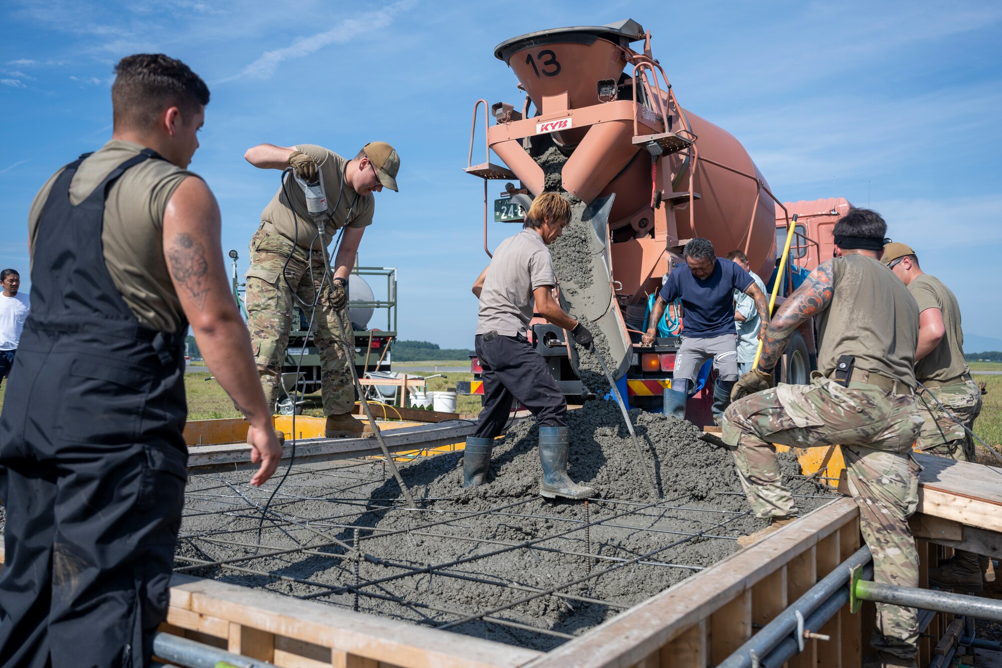 A group of people pouring cement into a frame.