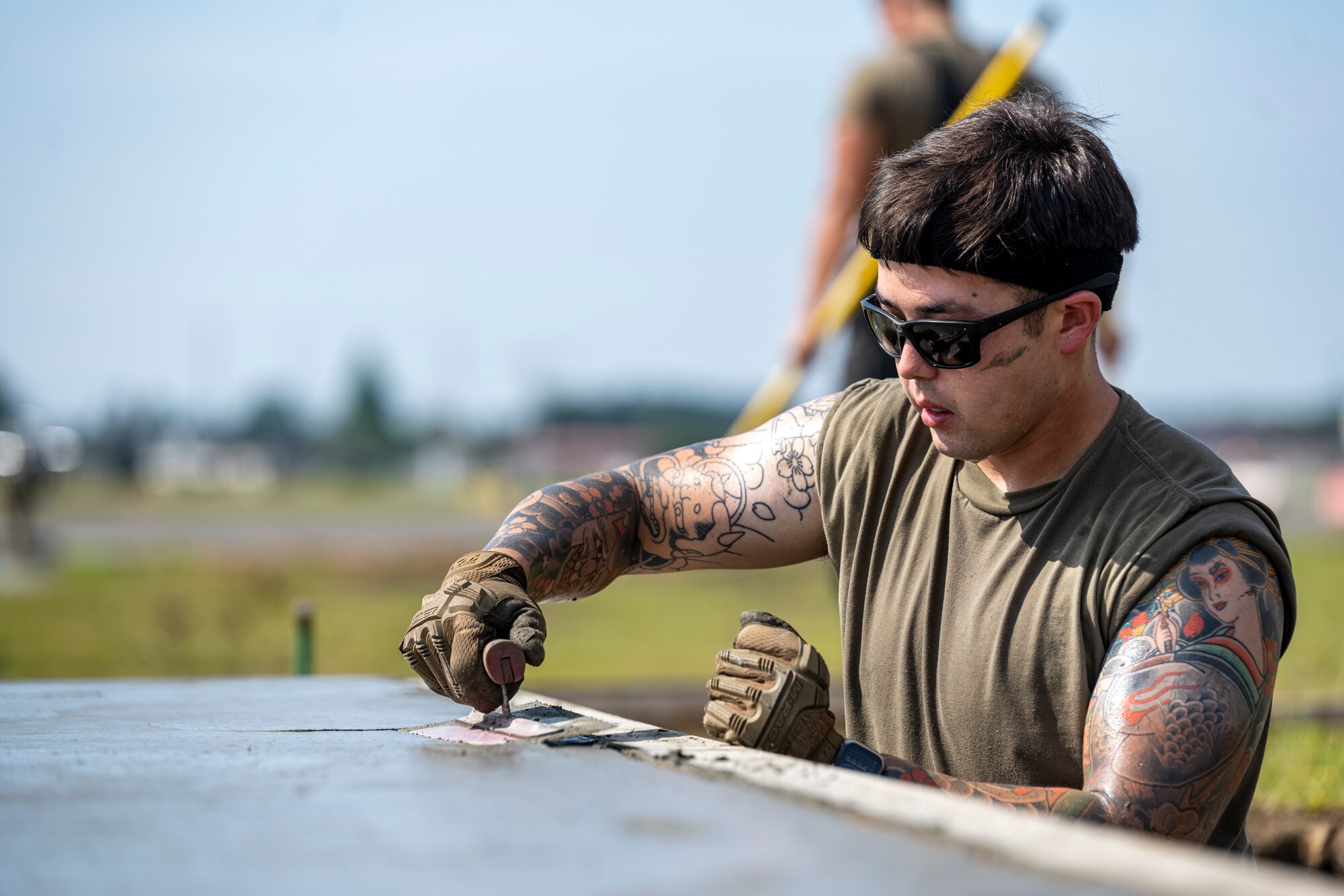 An Airman soothes wet concrete with a trowel.