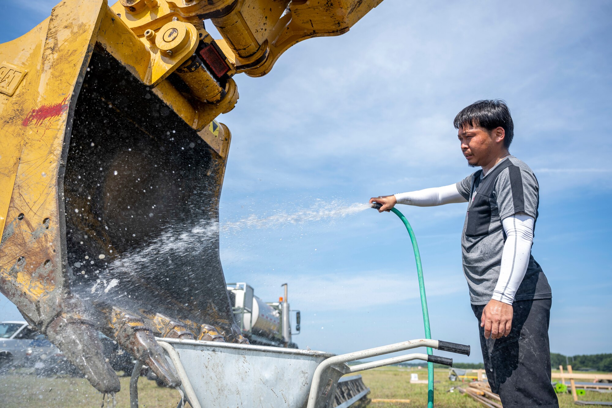 A Japanese man washes off the bucket of a excavator.