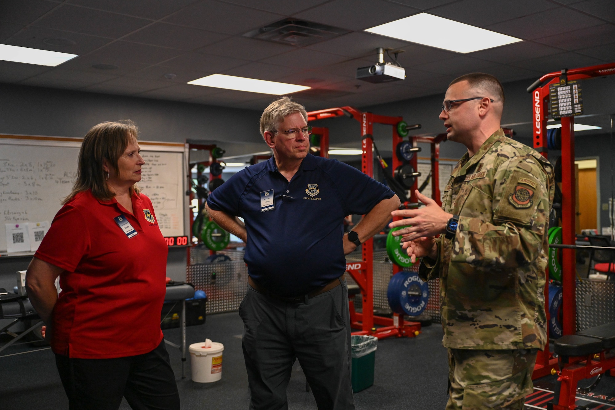 Two people stand with a man in uniform