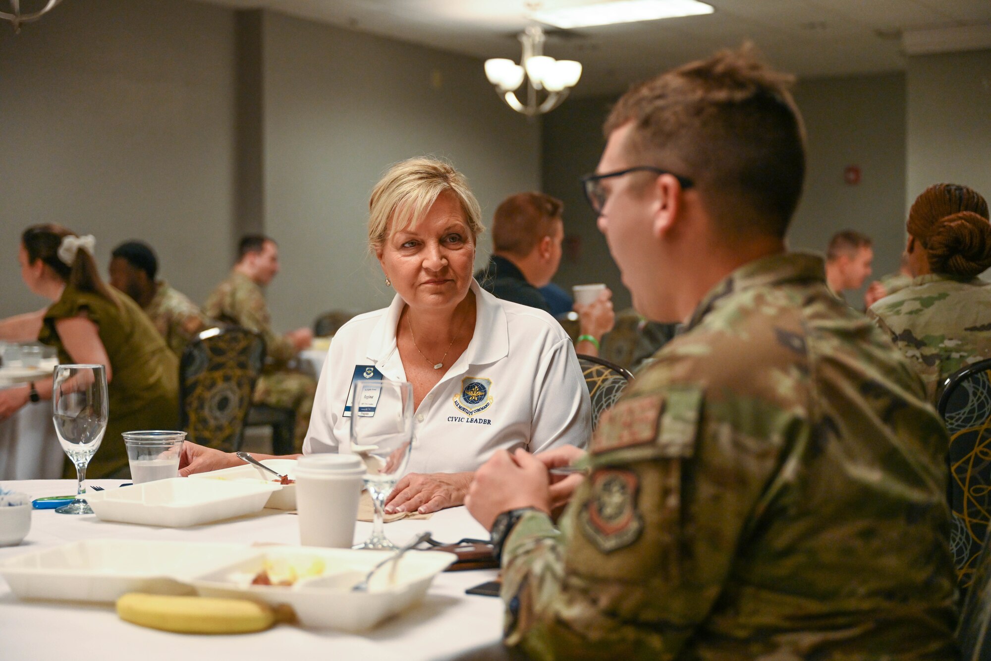 A woman eats food with a man in uniform