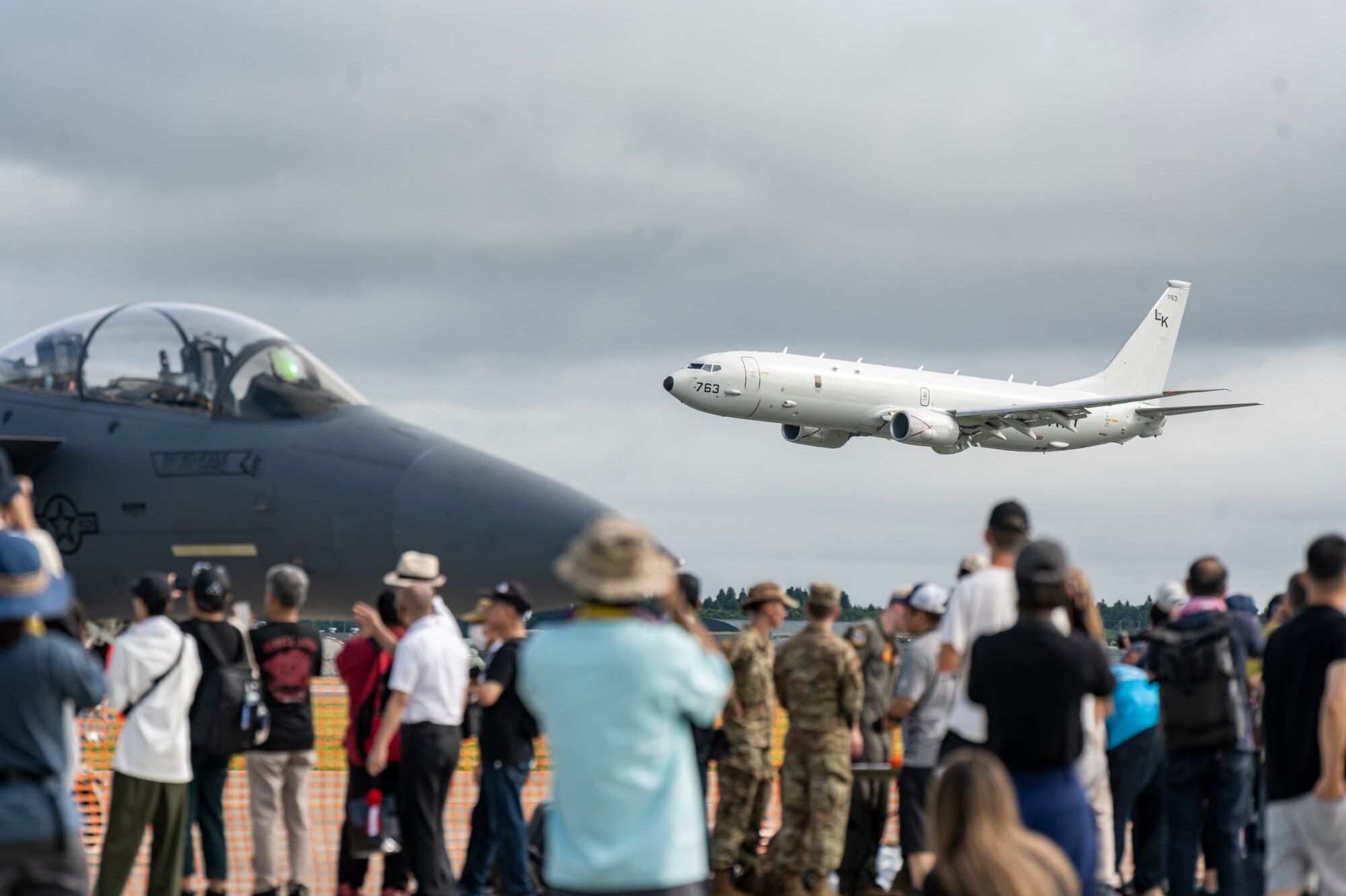 People watch as a plane takes off from the runway.