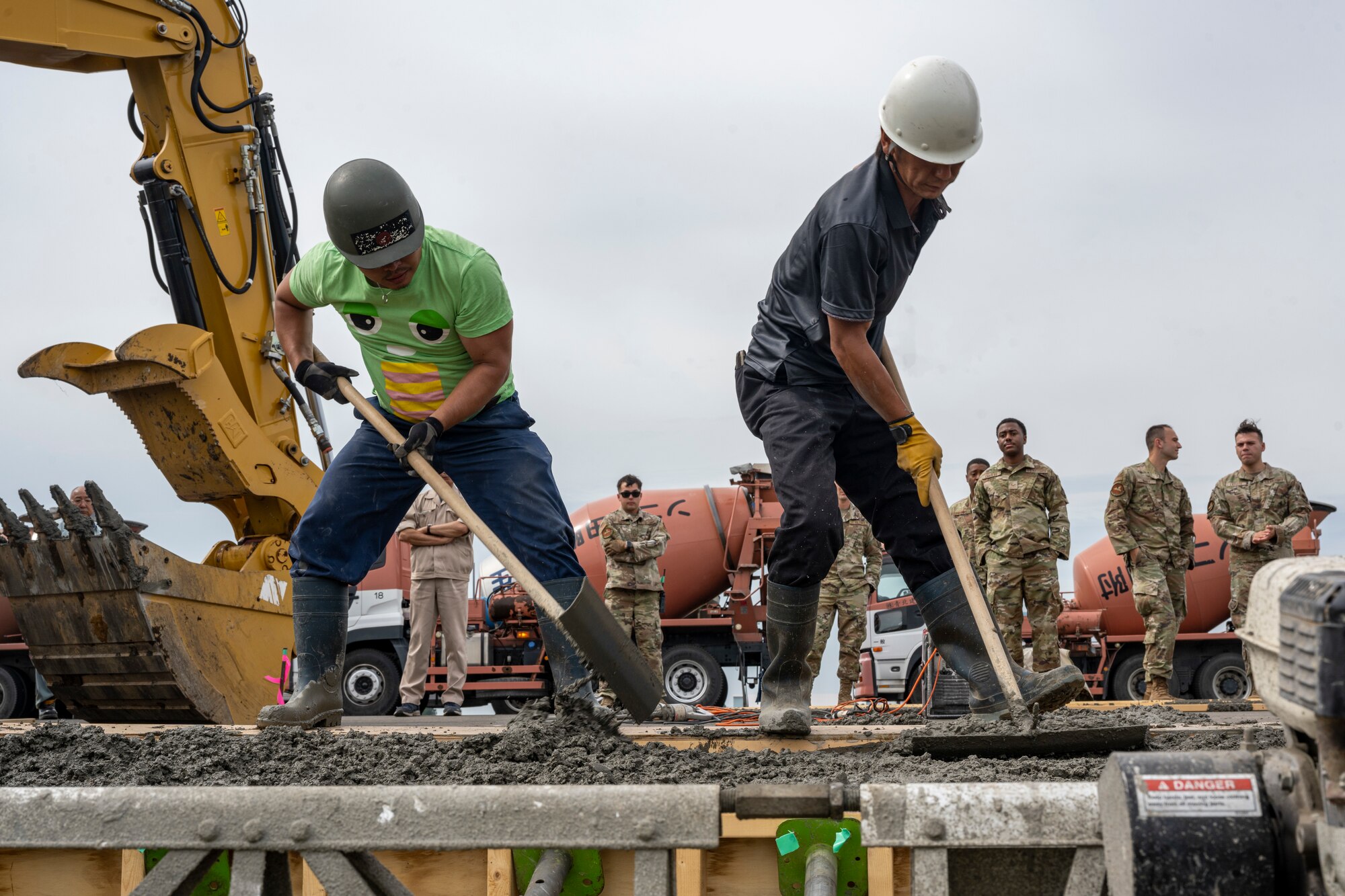Two men moving around wet cement inside of a frame.