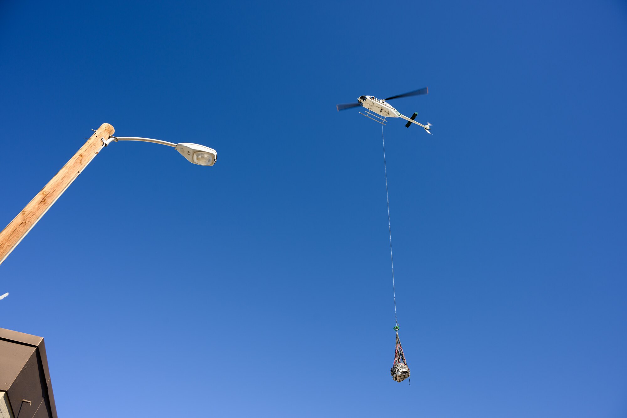 A photo of a capsule being lowered to the ground in a helicopter sling