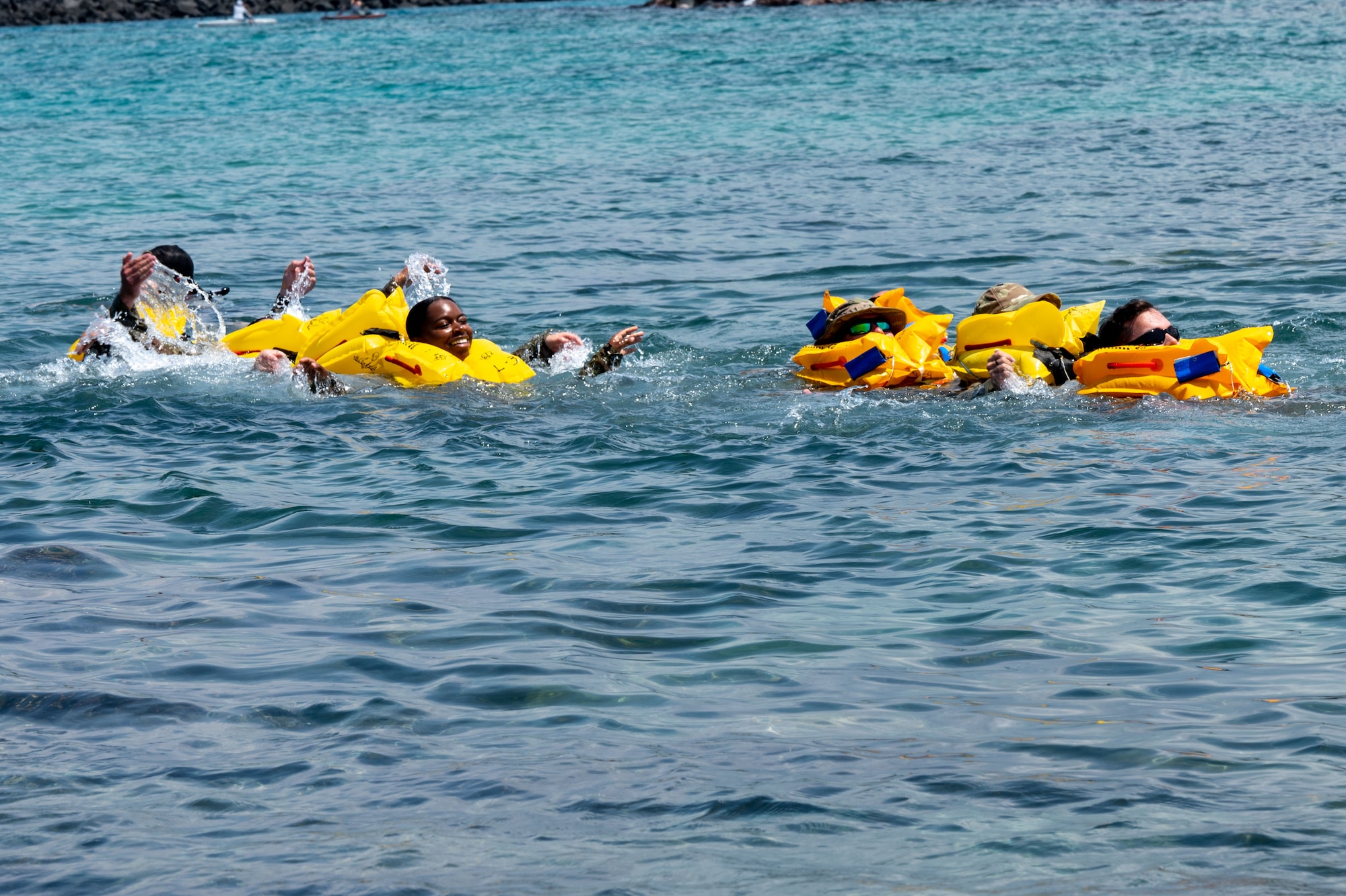 people in yellow life vests float in the water