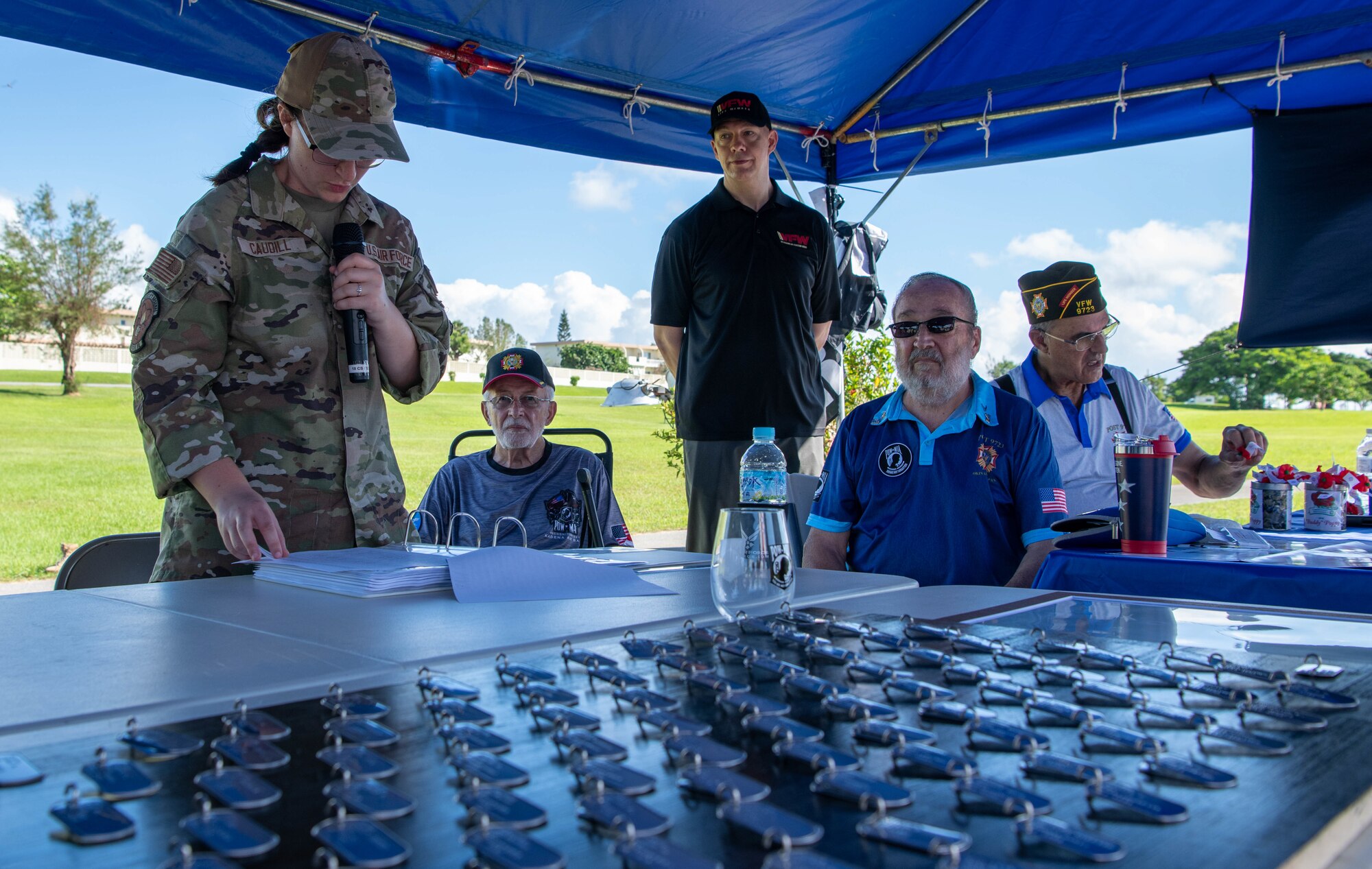 An Airman recites the names of those missing in action while retired veterans listen.