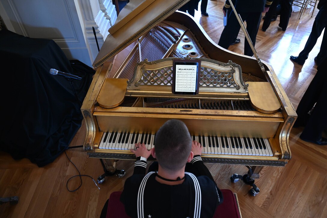 A sailor plays the piano as seen from above.