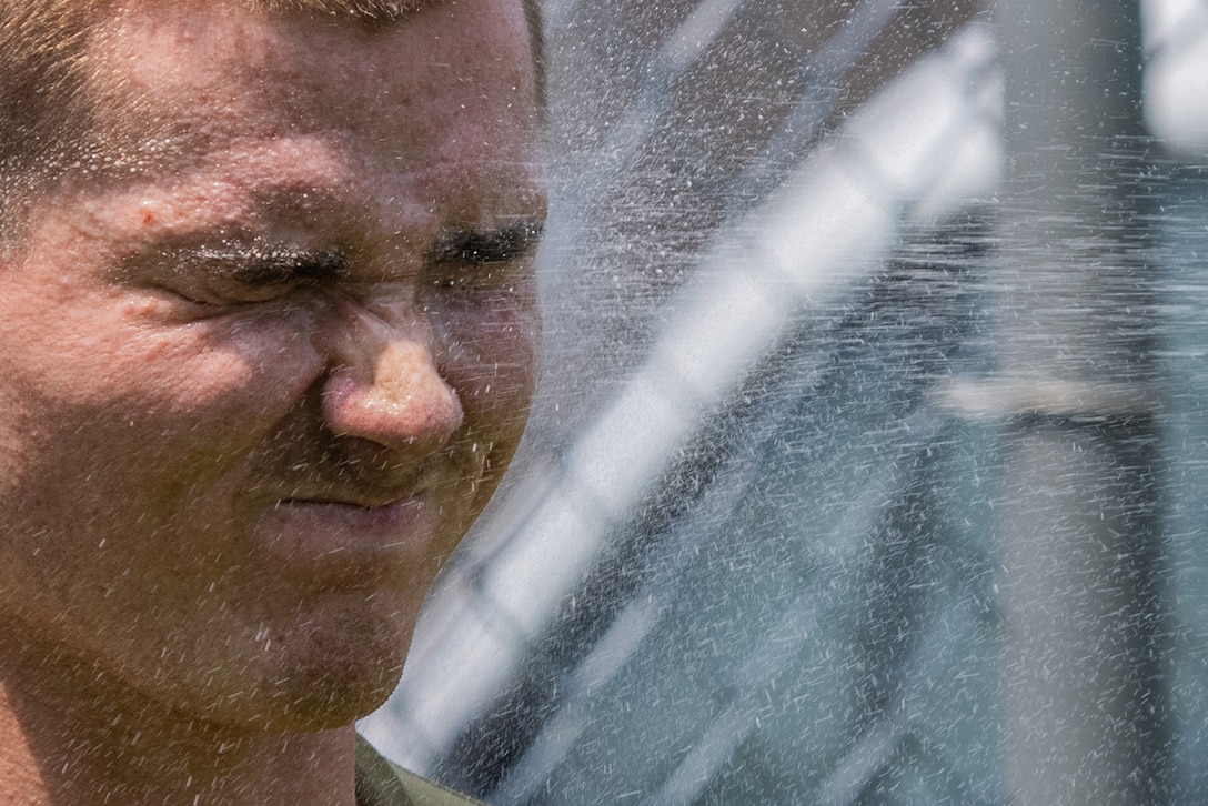 A Marine closes his eyes as he is covered with pepper spray.