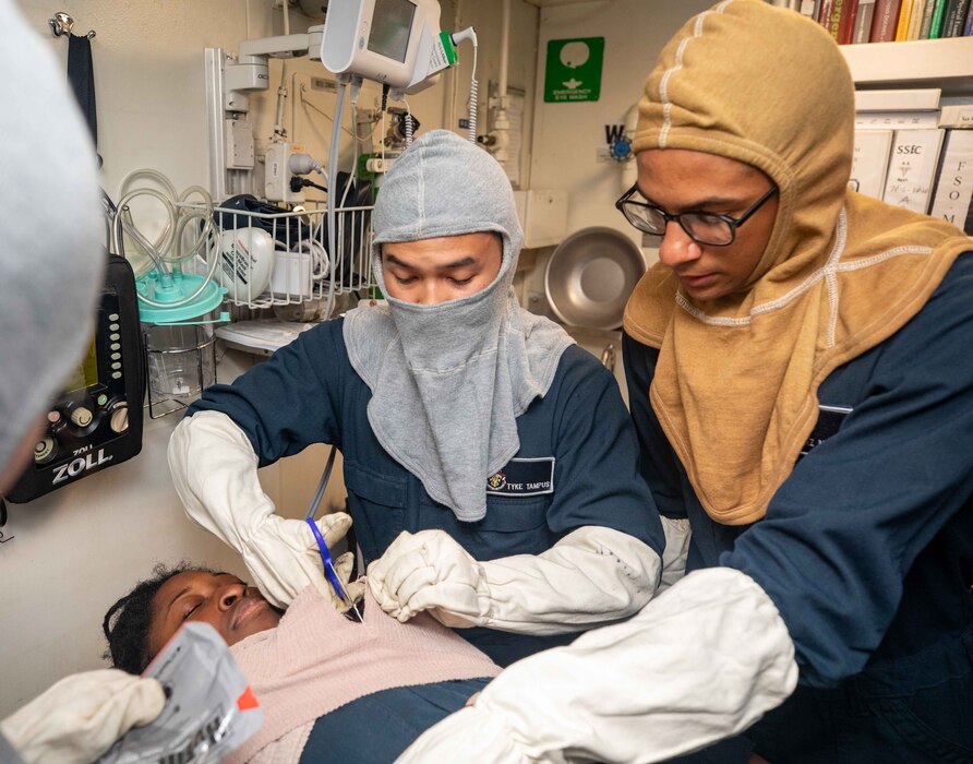 230919-N-KW492-2151 SAGAMI WAN 

Hospital Corpsman 2nd Class Tyke Tampus, from Cebu City, Philippines and Quartermaster 3rd Class Chaz Michel, from Troy, Ohio administers medical treatment to Quartermaster 3rd Class Ashante Essex, from Alexandria, Virginia, as she simulates an injury during a medical training drill aboard the Ticonderoga-class guided-missile cruiser USS Antietam (CG 54) conduct daily operations in Sagami Wan, Sept. 19, 2023. Antietam is assigned to Commander, Task Force (CTF) 70, and is forward-deployed to Yokosuka, Japan to support the security of the U.S. and its Allies in the Indo-Pacific. (U.S. Navy photo by Mass Communication Specialist 1st Class Ryre Arciaga)