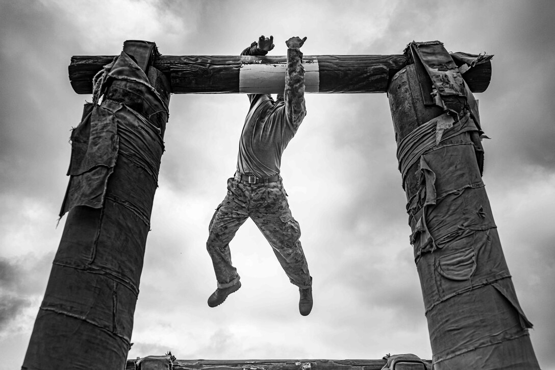 A recruit attempts to hold onto a log obstacle.