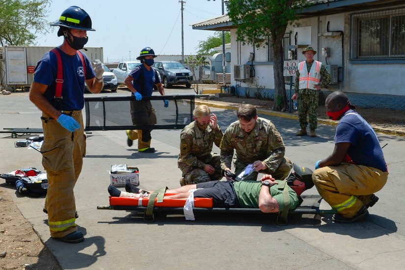 Emergency personnel perform treatment on someone with simulated injuries.