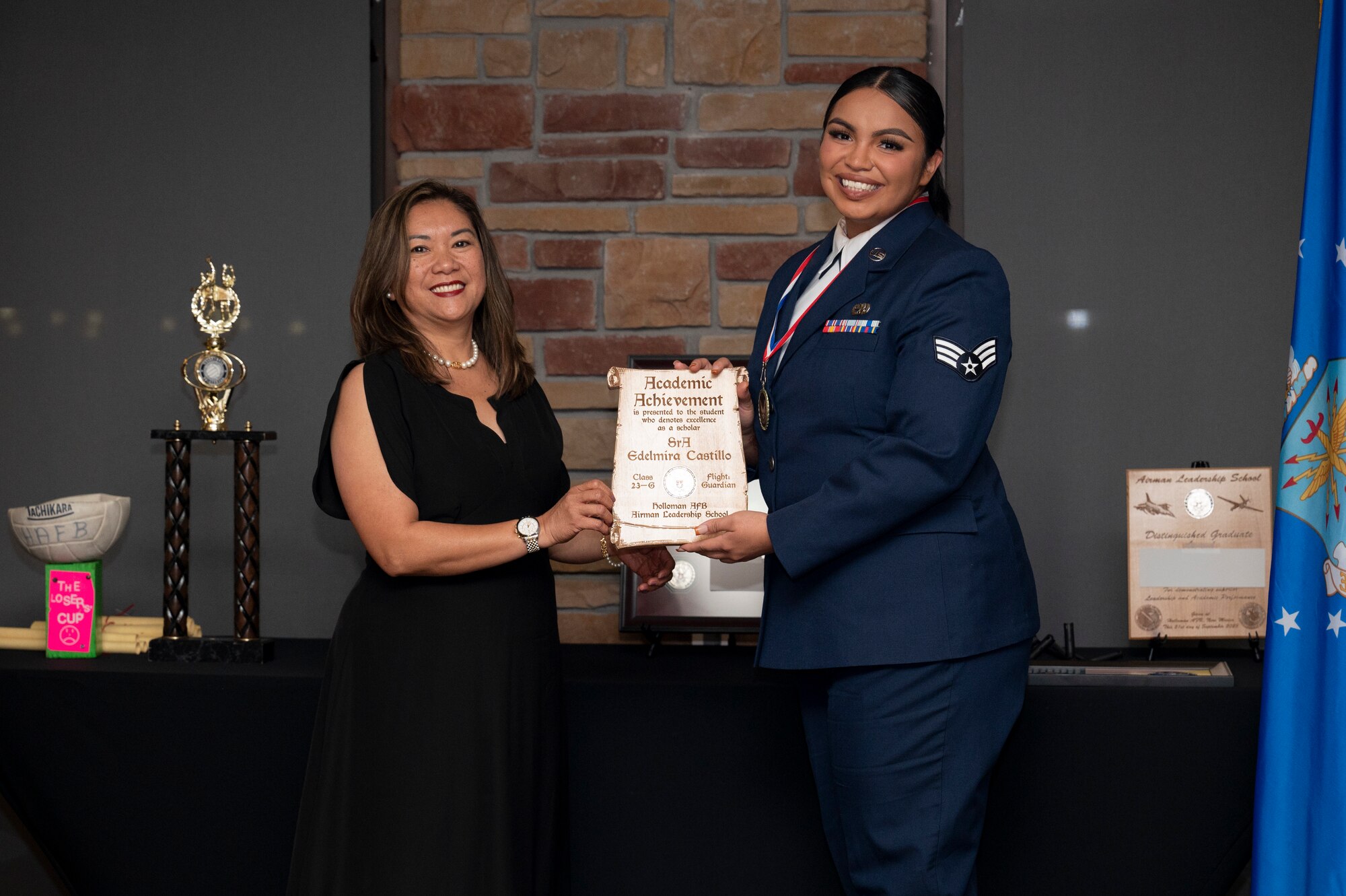 U.S. Air Force Senior Airman Edelmira Castillo, right, Airman Leadership Graduate, accepts Academic Achievement Award from Ms. Lany Cooper, during the graduation of MAYO ALS Class 23-G at Holloman Air Force Base, New Mexico, Sep. 21, 2023. The academic award is presented to the student with the highest overall average on all academic evaluations and demonstrations of leadership. (U.S. Air Force photo by Airman 1st Class Michelle Ferrari)