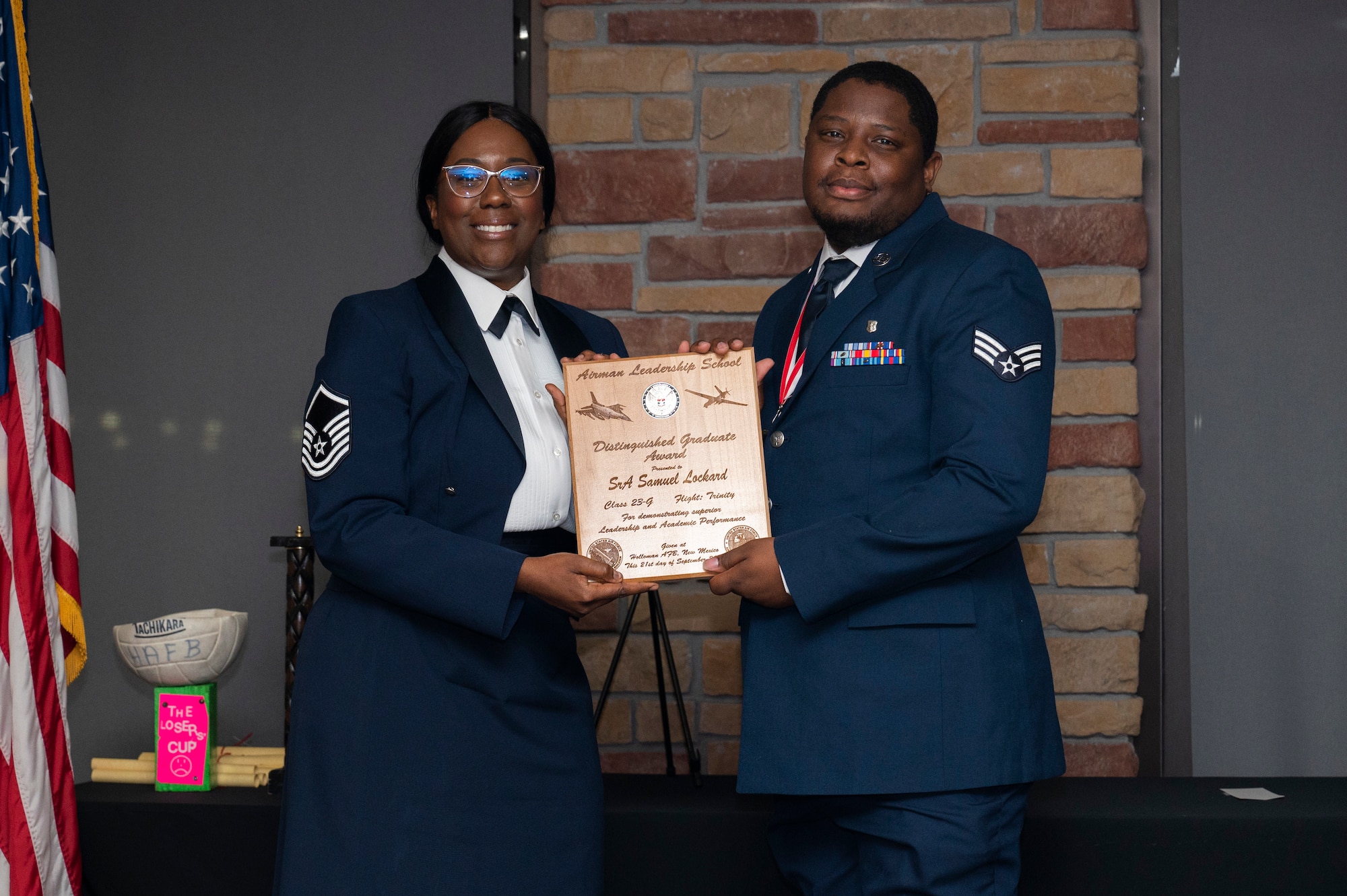 U.S. Air Force Senior Airman Samuel Lockard, right, Airman Leadership Graduate, accepts the Distinguished Graduate Award from Holloman Top III representative Master Sgt. Deshona Crowder during the graduation of MAYO ALS Class 23-G at Holloman Air Force Base, New Mexico, Sep. 21, 2023. The distinguished graduate award is presented to the top 10% of graduates for their performance in academic evaluations and demonstration of leadership. (U.S. Air Force photo by Airman 1st Class Michelle Ferrari)