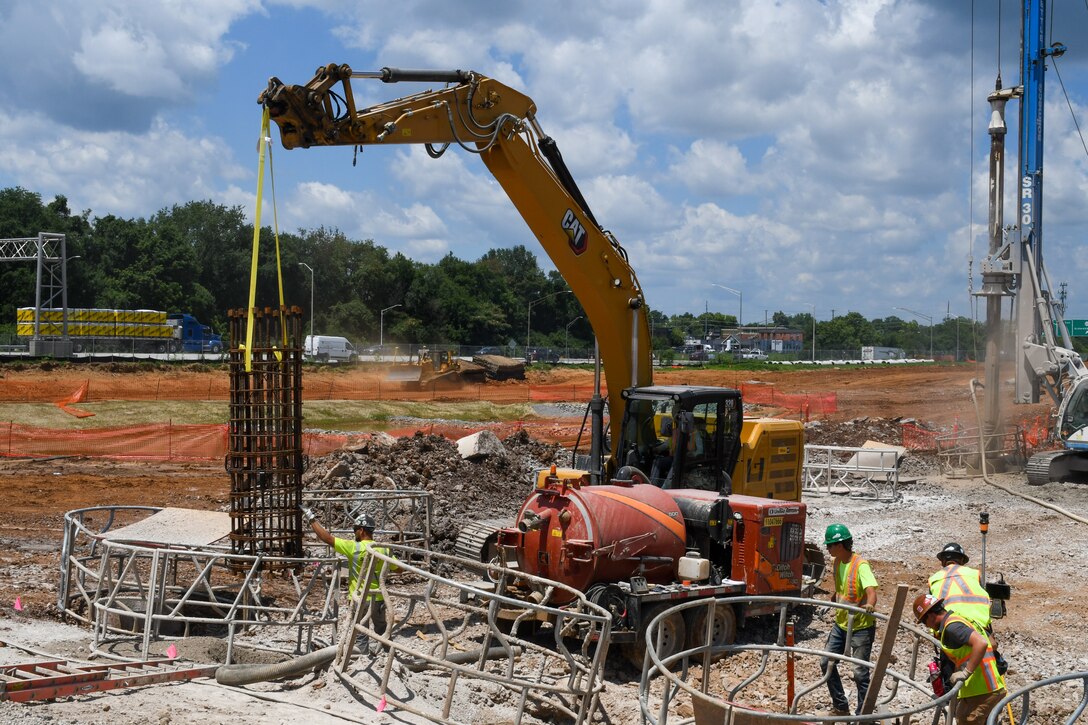 Photo shows workers installing a rebar cage into a drill hole in the earth.