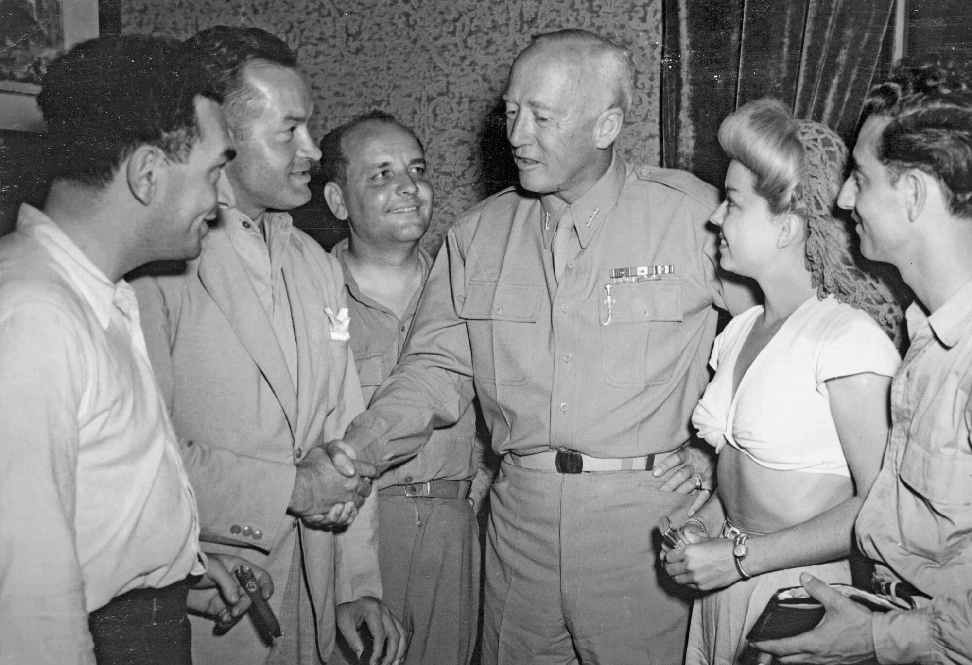 Two men shake hands as others look on.