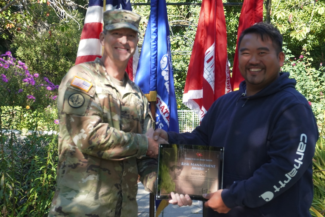 An Army officer presents an award to a civilian in the rose garden of Lake Washington Ship Canal and Hiram M. Chittenden Locks, Seattle, Washington.