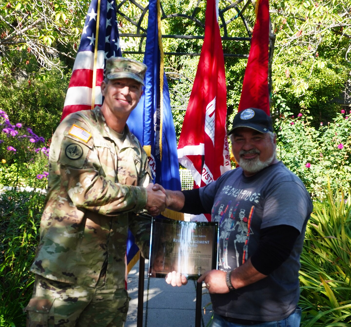 An Army officer presents an award to a civilian in the rose garden of Lake Washington Ship Canal and Hiram M. Chittenden Locks, in Seattle, Washington.