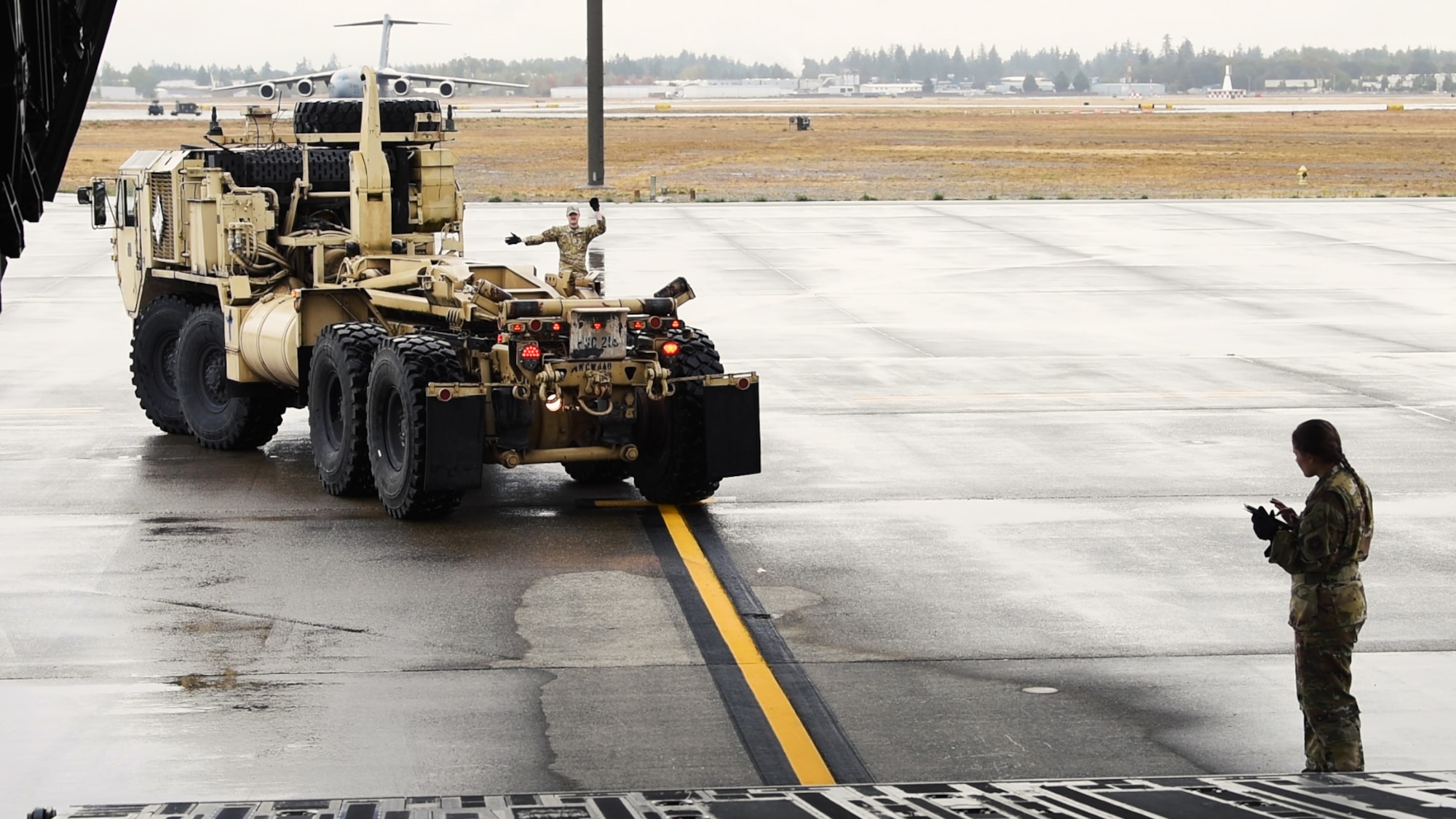 U.S. Air Force Airman 1st Class Vallery Stavish, right, and Senior Airman Kainoa Cook, center, both loadmasters with the 4th Expeditionary Airlift Squadron, guide a U.S. Army Heavy Expanded Mobility Tactical Truck onto a C-17A Globemaster III during Exercise Rainier War 23A at Joint Base Lewis-McChord, Washington, Sept. 20, 2023. The 4th EAS trained alongside U.S. Soldiers from the 555th Engineer Brigade at JBLM, Washington, to upload military vehicles onboard a C-17, as well as how to secure the vehicles during flights. Rainier War is an annual exercise led by the 62d Airlift Wing designed to evaluate the ability to generate, employ and sustain in-garrison and forward deployed forces. (U.S. Air Force photo by Staff Sgt. Zoe Thacker)