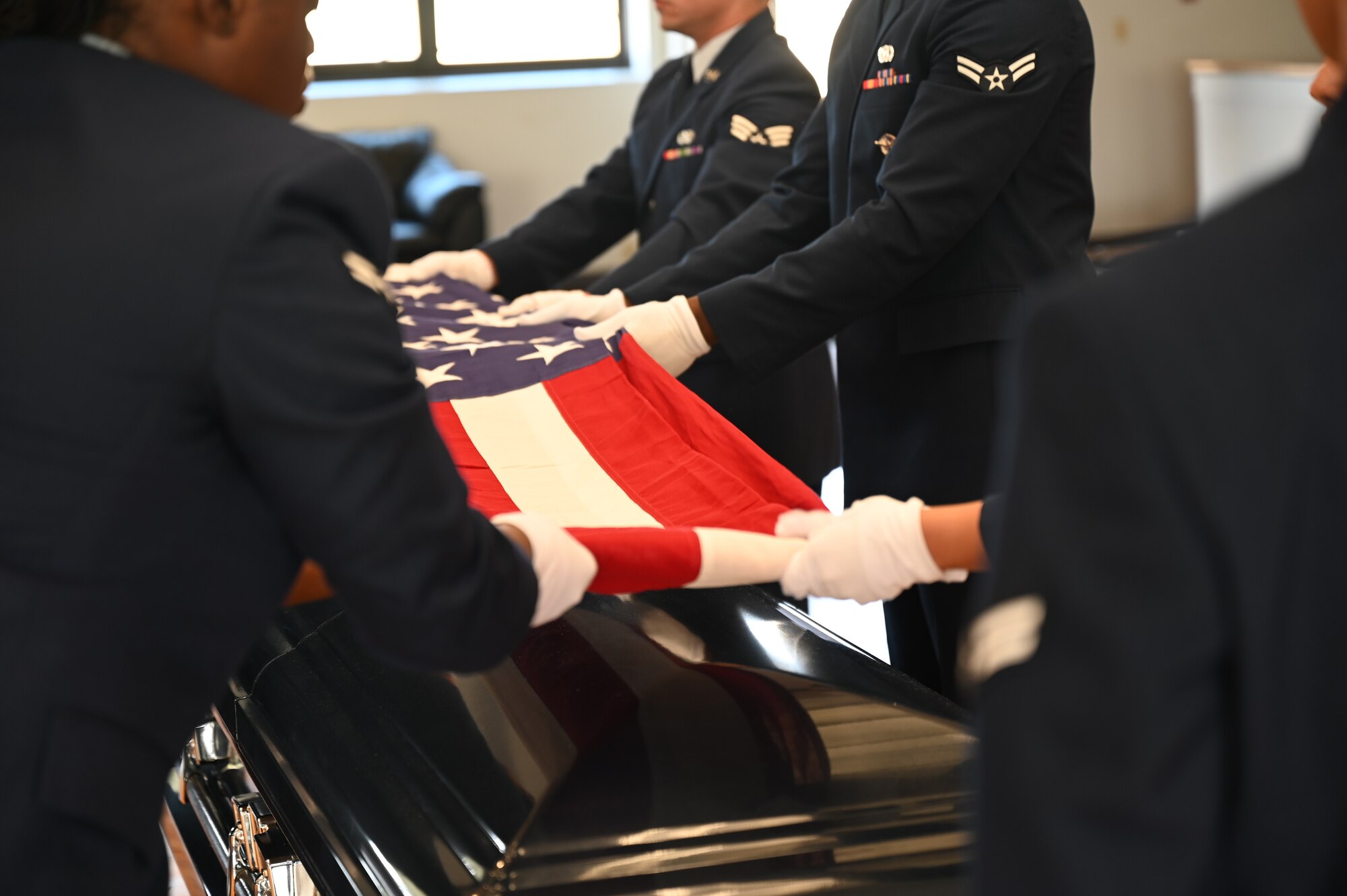 Image of the hands of Honor Guardsmen folding the flag over a ceremonial casket