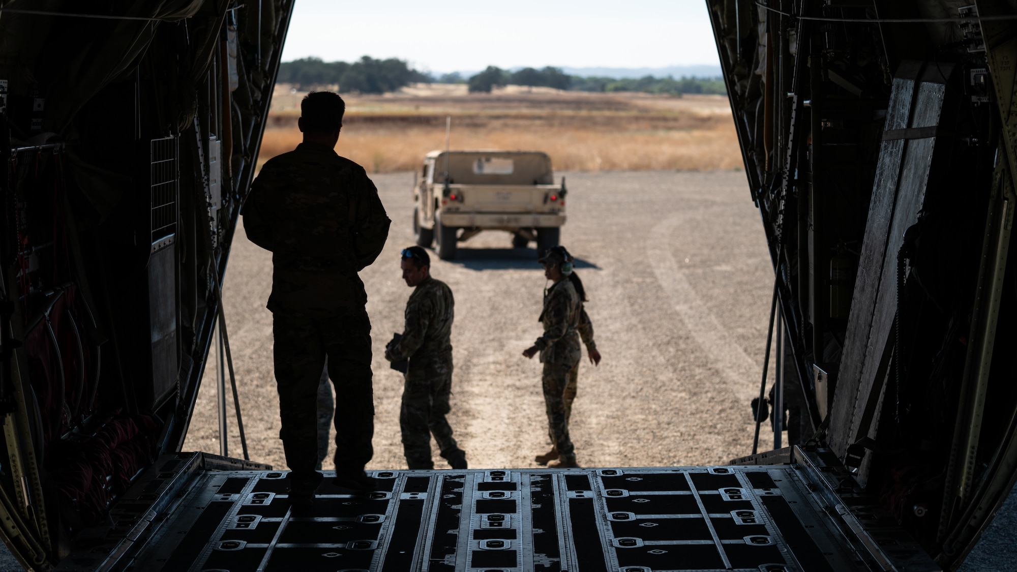 Senior Master Sgt. Jame McGowen observes Airman 1st Class Christopher Robles and Airman 1st Class Laura Ochoa, assigned to the 115th Airlift Squadron, before they assist in loading a California Army National Guard Humvee during an exercise at Schoonover Airfield, Fort Hunter Liggett, California, Sept. 9, 2023. The exercise, also known as Crisis Beach II, was a multi-day exercise to evaluate the 146th Airlift Wing's ability to deploy, adapt, and survive in a contested environment. Airmen participating implemented many skill sets shared from other career fields to demonstrate their ability to execute the Agile Combat Employment (ACE) model, highlighting their proactive and reactive operational strategies under simulated threat timelines in order to increase survivability while generating combat power. (U.S. Air National Guard photo by Maj. Andrei Mostovoj)