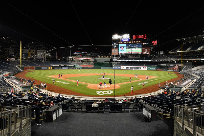 Wide view of the field of Nationals Park where the players are playing in the softball championship. Fans can be seen sitting in the stands.