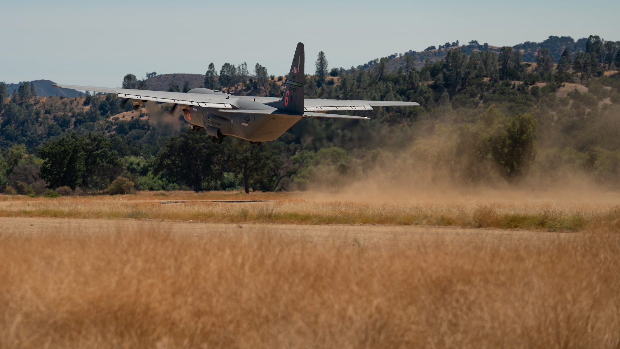 A California Air National Guard C-130J Super Hercules aircraft assigned to the 115th Airlift Squadron departs a tactical runway during an exercise at Schoonover Airfield, Fort Hunter Liggett, California, Sept. 9, 2023. The exercise, also known as Crisis Beach II, was a multi-day exercise to evaluate the 146th Airlift Wing's ability to deploy, adapt, and survive in a contested environment. Airmen participating implemented many skill sets shared from other career fields to demonstrate their ability to execute the Agile Combat Employment (ACE) model, highlighting their proactive and reactive operational strategies under simulated threat timelines in order to increase survivability while generating combat power. (U.S. Air National Guard photo by Maj. Andrei Mostovoj)