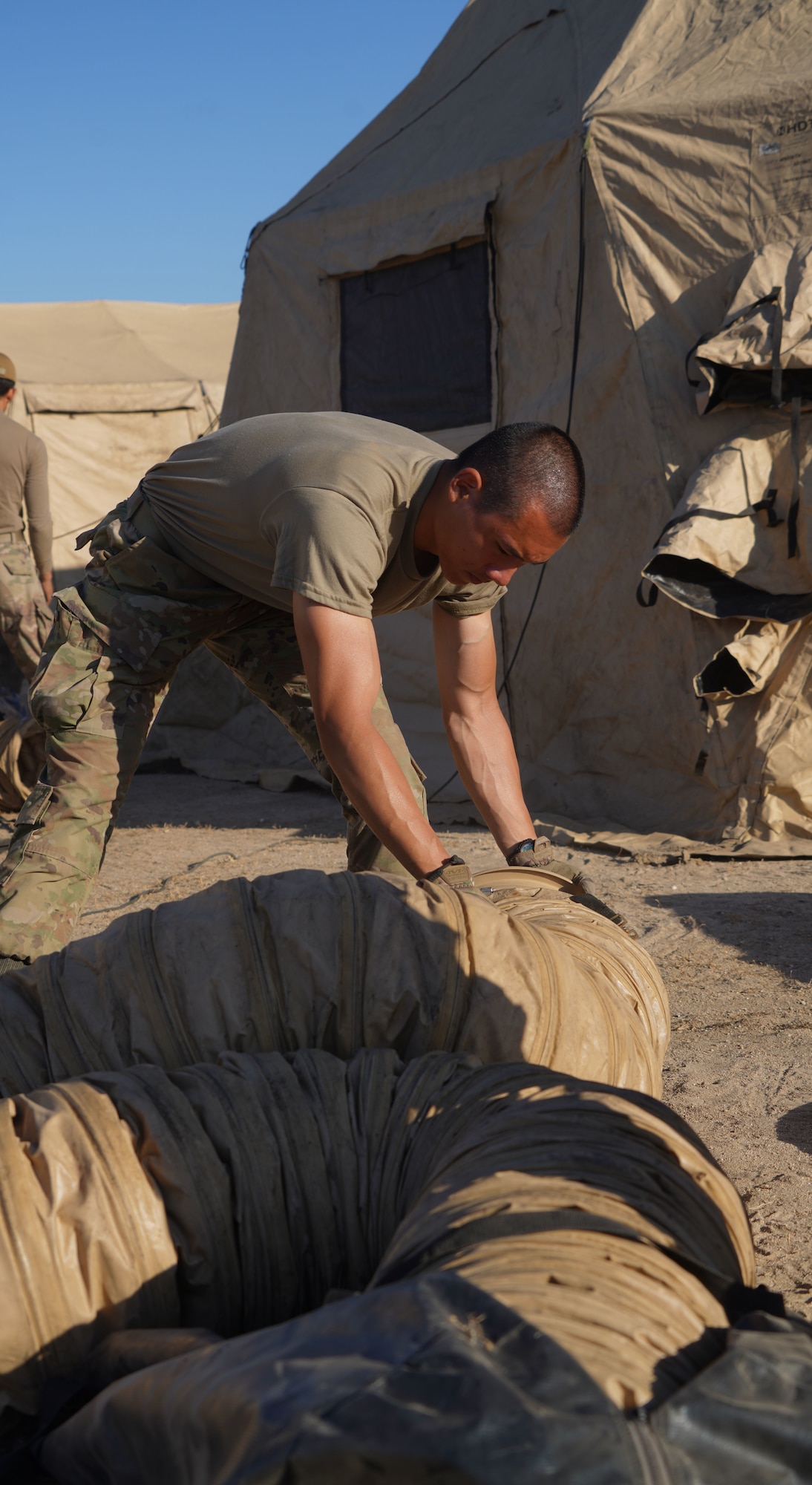 U.S. Air National Guard Senior Airman Shahin Mellati, a civil engineer with the 146th Airlift Wing’s Civil Engineer Squadron, breaks down a tent during a readiness exercise at Fort Hunter-Ligget, California, September 9, 2023. The 146th’s Civil Engineering Squadron arrived at the exercise a day before the main exercise body to construct a tent city for the arriving Airmen. The exercise, also known as Crisis Beach II, was a multi-day exercise to evaluate the 146th Airlift Wing's ability to deploy, adapt, and survive in a contested environment. Airmen participating implemented many skill sets shared from other career fields to demonstrate their ability to execute the Agile Combat Employment (ACE) model, highlighting their proactive and reactive operational strategies under simulated threat timelines in order to increase survivability while generating combat power. (U.S. Air National Guard photo by Staff Sgt. Michelle Ulber)