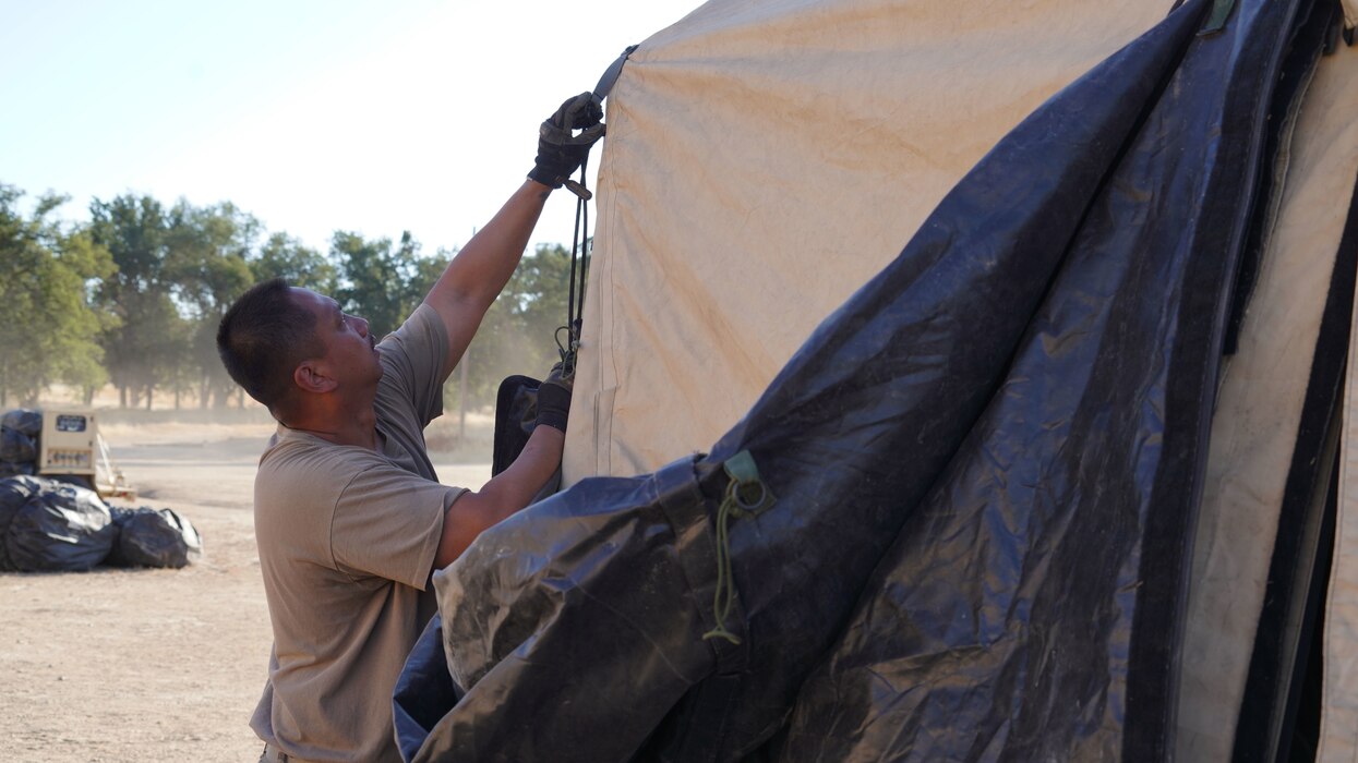 U.S. Air National Guard Staff Sgt. Alan Montague, a civil engineer with the 146th Airlift Wing’s Civil Engineer Squadron, breaks down a tent during a readiness exercise at Fort Hunter-Ligget, California, September 9, 2023. The 146th’s Civil Engineering Squadron arrived at the exercise a day before the main exercise body to construct a tent city for the arriving Airmen. The exercise, also known as Crisis Beach II, was a multi-day exercise to evaluate the 146th Airlift Wing's ability to deploy, adapt, and survive in a contested environment. Airmen participating implemented many skill sets shared from other career fields to demonstrate their ability to execute the Agile Combat Employment (ACE) model, highlighting their proactive and reactive operational strategies under simulated threat timelines in order to increase survivability while generating combat power. (U.S. Air National Guard photo by Staff Sgt. Michelle Ulber)