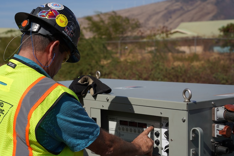 A man in a hardhat inspects a power generator