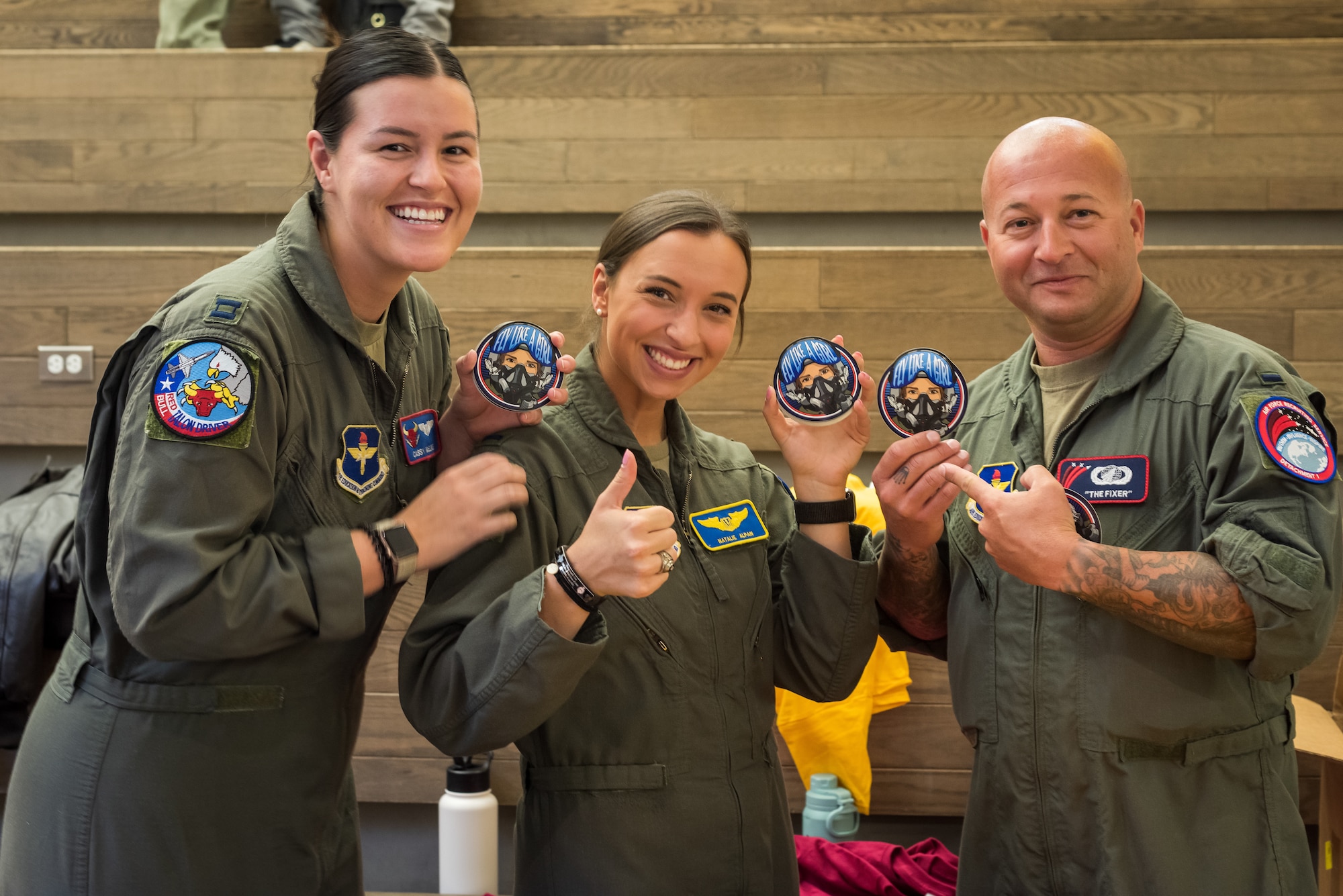 (From left) U.S. Air Force Capt. Cassandra McElwee, 1st Lt. Natalie Alpan, and 1st Lt. Ryan Kenney distribute “Fly Like a Girl” stickers during a recruiting visit at Kodiak High School, in Kodiak, Alaska, Sept. 6, 2023.