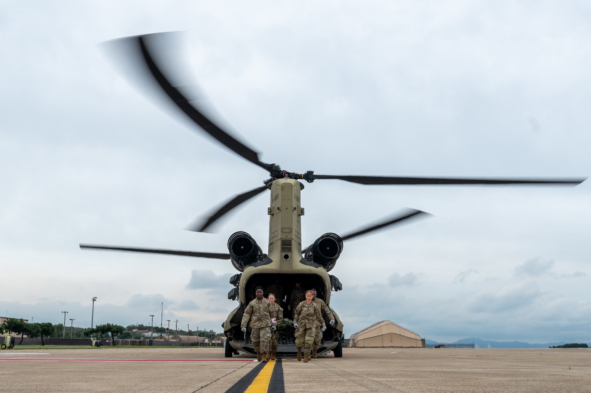 Airmen from the 8th Medical Group exit a U.S. Army CH-47 Chinook while carrying a medical training mannequin upon conclusion of a joint medical evacuation training