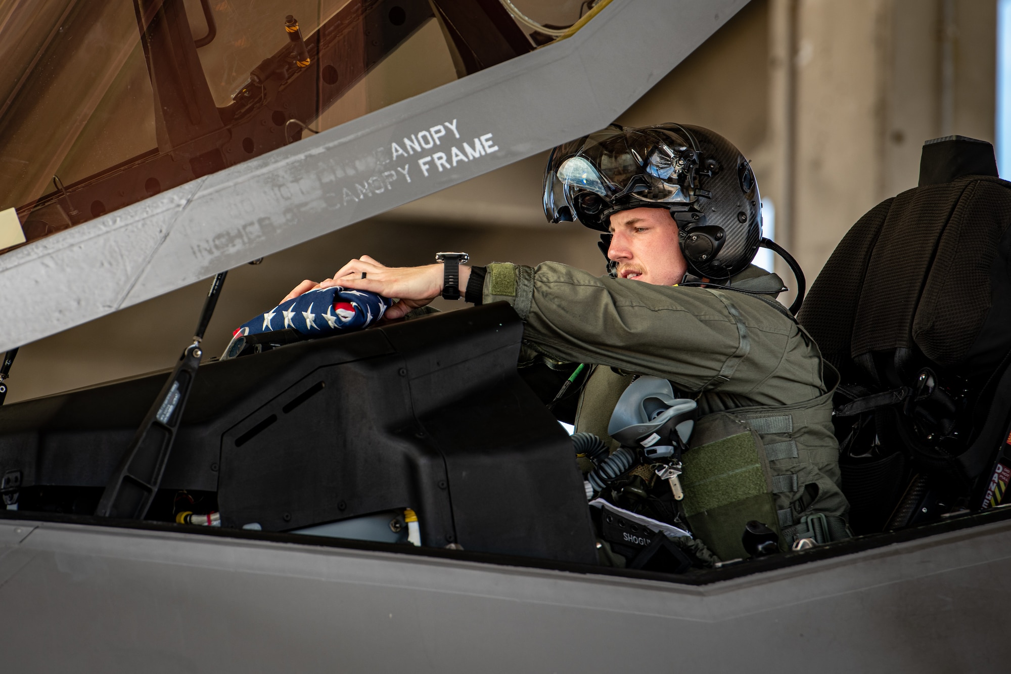 A pilot sets a folded American flag on the dash of an F-15C Eagle.