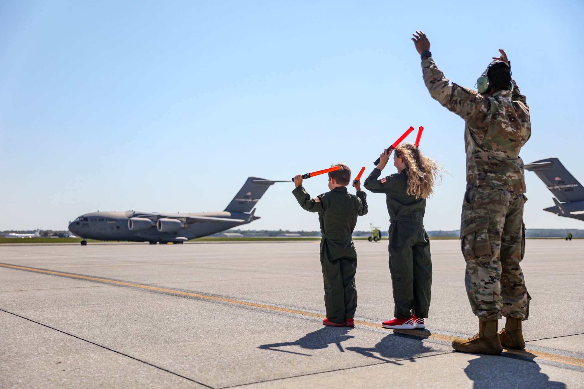 The children of Col. Nathan Day, 445th Airlift Wing deputy commander, marshal his C-17 Globemaster III in after landing at Wright-Patterson Air Force Base, Ohio for his final C-17 flight Sept. 22, 2023.