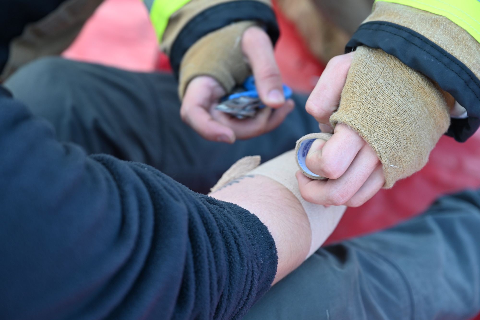 U.S. Air Force Airman 1st Class Jacob Meyer, right, 100th Civil Engineer Squadron Fire Department firefighter, secures a bandage on a simulated casualty during a natural disaster mass care exercise at Royal Air Force Mildenhall, England, Sept. 21, 2023. During the exercise scenario, firefighters and 100th Security Forces Squadron defenders performed search and rescue operations, and ensured mock casualties were safe and cared for. (U.S. Air Force photo by Karen Abeyasekere)