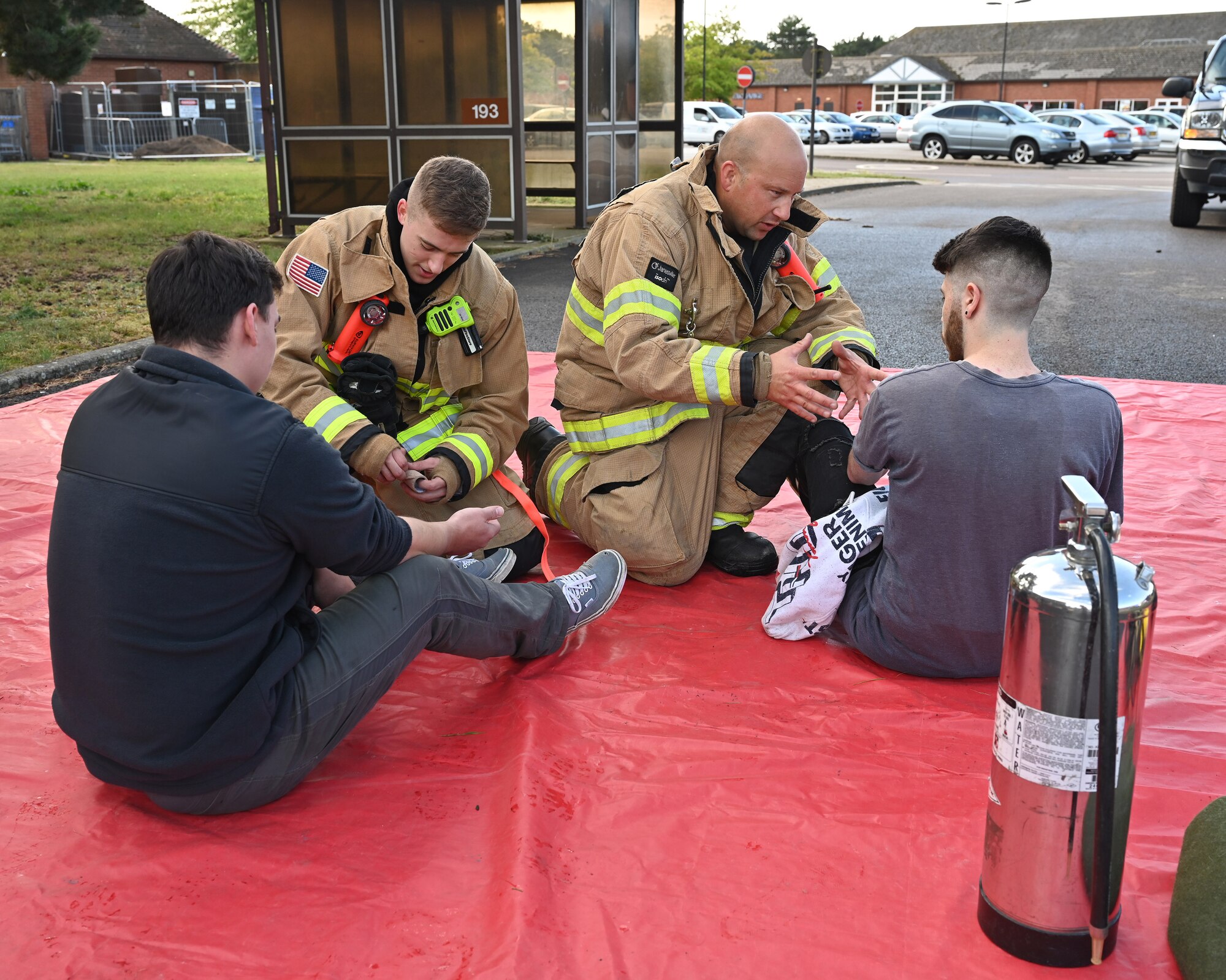 U.S. Air Force Airman 1st Class Jacob Meyer, left, 100th Civil Engineer Squadron Fire Department firefighter, and Charlie Browne, 100th CES Fire Department driver operator, talk to mock patients and give medical care during a natural disaster mass care exercise at Royal Air Force Mildenhall, England, Sept. 21, 2023. During the exercise scenario, firefighters and 100th Security Forces Squadron defenders performed search and rescue operations, and ensured simulated casualties were safe and cared for. (U.S. Air Force photo by Karen Abeyasekere)
