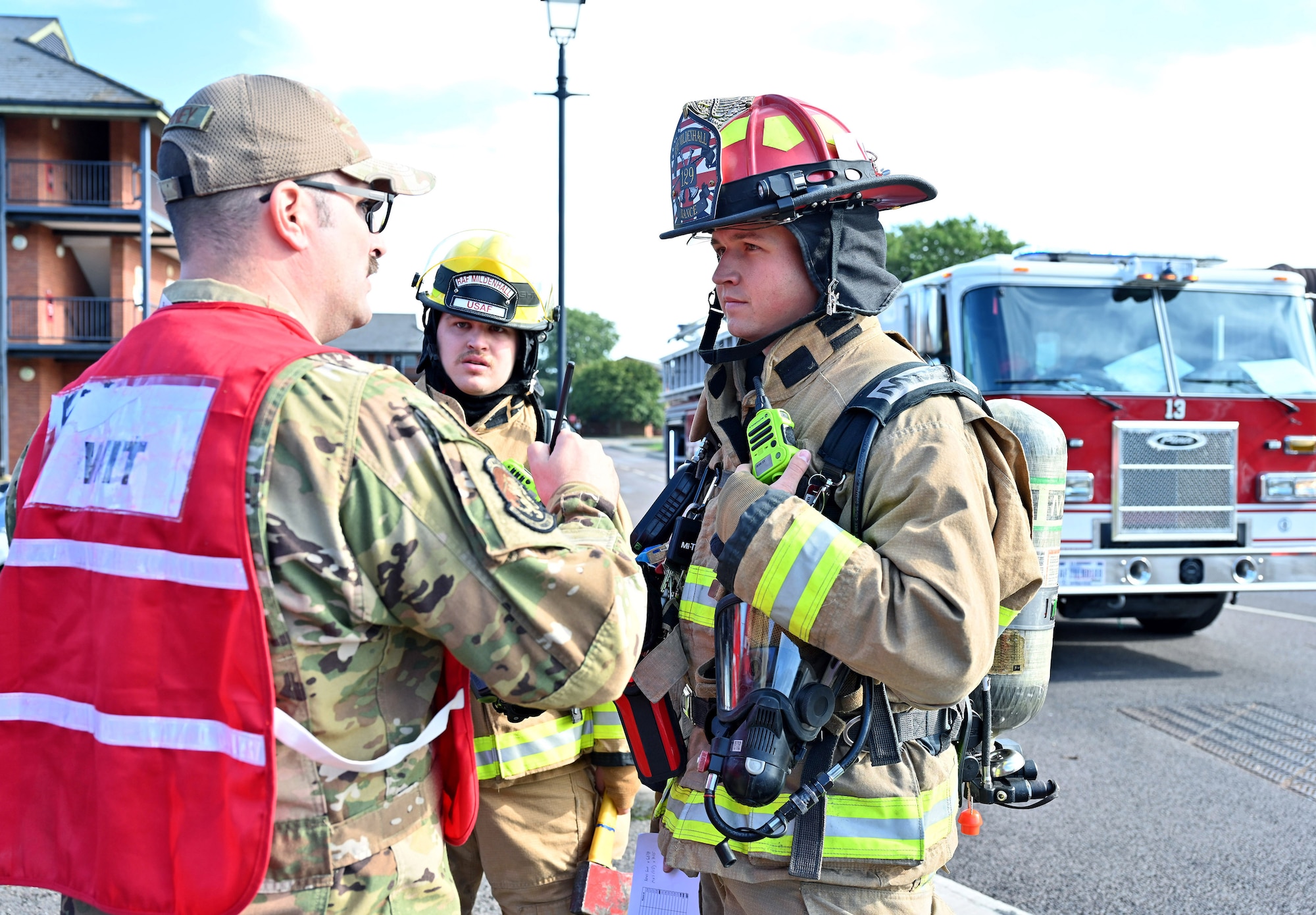A wing inspection team member assigned to the 100th Air Refueling Wing shares information with 100th Civil Engineer Squadron firefighters during a scenario as part of a natural disaster mass care exercise at Royal Air Force Mildenhall, England, Sept. 21, 2023. The exercise allowed firefighters and 100th Security Forces Squadron defenders to practice performing essential operations during a simulated natural disaster incident. (U.S. Air Force photo by Karen Abeyasekere)