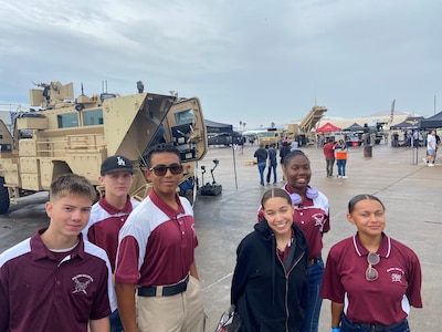 Students pose in front of Army vehicle.