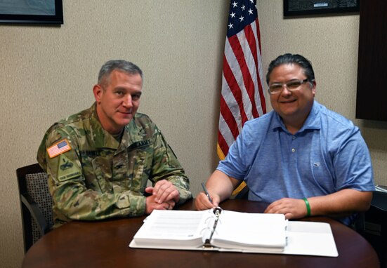 A man wears a military uniform, and another man wears a blue shirt.