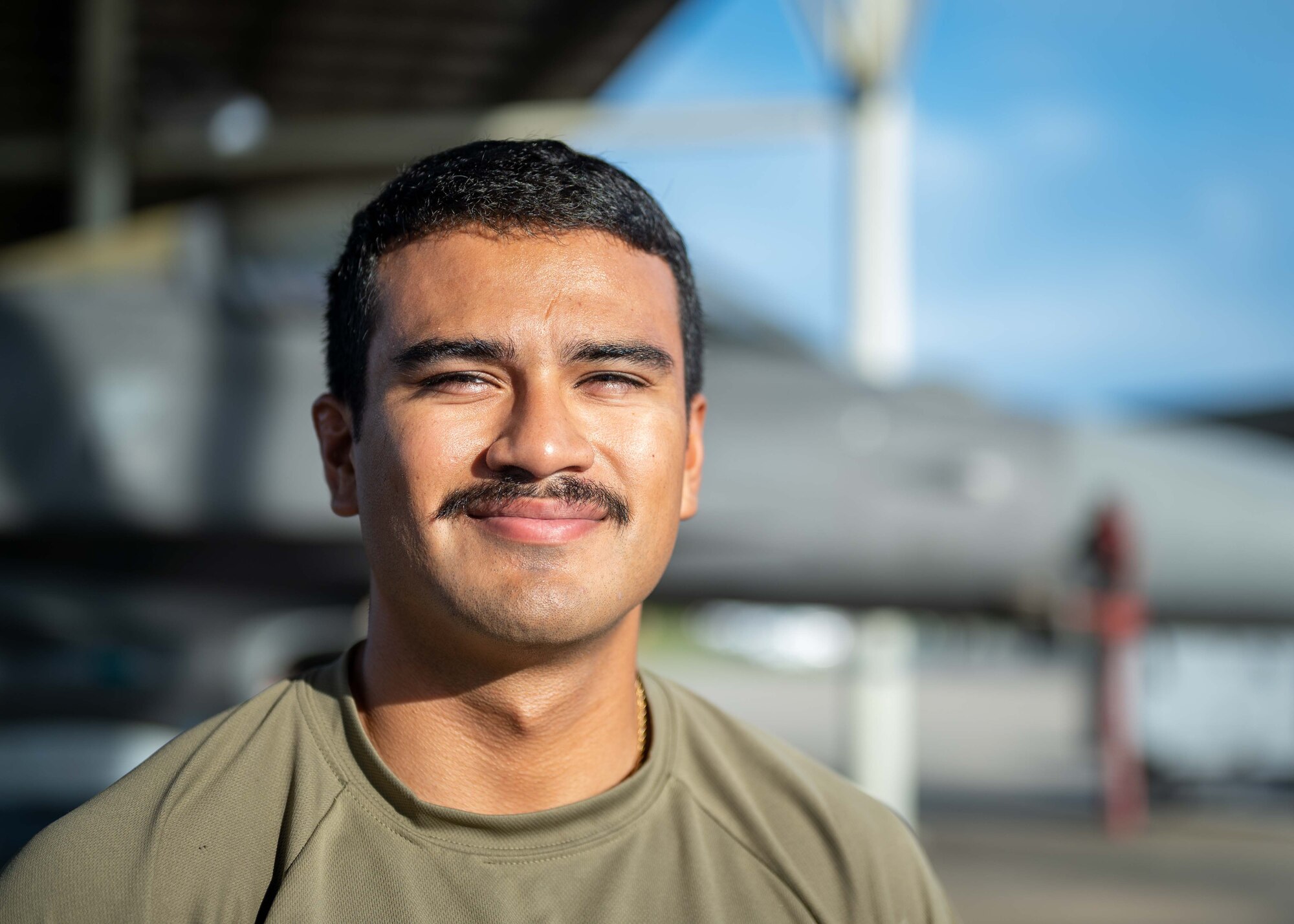 A crew chief smiles for a portrait on the flightline.
