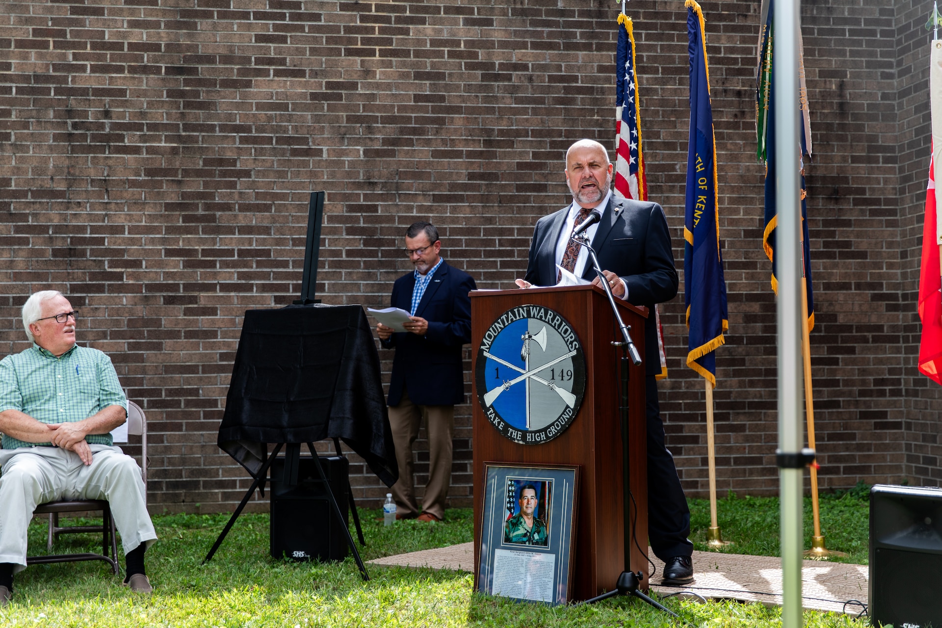 The wife of 1st Sgt. Ottis W. Capps, Sherry [left] and their two sons, Jeff and Jason, unveil the new bronze plaque at the Harlan National Guard Armory in Harlan, Kentucky on Sept. 21, 2023. The National Guard armory was named after 1st Sgt. Ottis W. Capps who served as the Alpha Company, 1-149th Infantry full-time support for over 30 years and was a cornerstone of the Harlan National Guard community during his career. (U.S. Army National Guard photo by Andy Dickson)