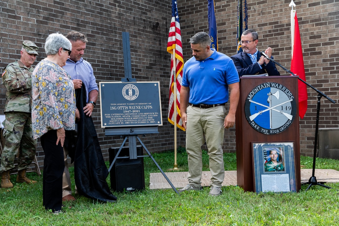 The wife of 1st Sgt. Ottis W. Capps, Sherry [left] and their two sons, Jeff and Jason, unveil the new bronze plaque at the Harlan National Guard Armory in Harlan, Kentucky on Sept. 21, 2023. The National Guard armory was named after 1st Sgt. Ottis W. Capps who served as the Alpha Company, 1-149th Infantry full-time support for over 30 years and was a cornerstone of the Harlan National Guard community during his career. (U.S. Army National Guard photo by Andy Dickson)
