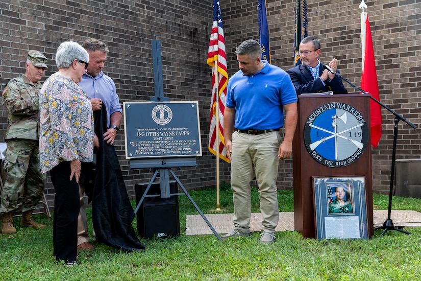 The wife of 1st Sgt. Ottis W. Capps, Sherry [left] and their two sons, Jeff and Jason, unveil the new bronze plaque at the Harlan National Guard Armory in Harlan, Kentucky on Sept. 21, 2023. The National Guard armory was named after 1st Sgt. Ottis W. Capps who served as the Alpha Company, 1-149th Infantry full-time support for over 30 years and was a cornerstone of the Harlan National Guard community during his career. (U.S. Army National Guard photo by Andy Dickson)