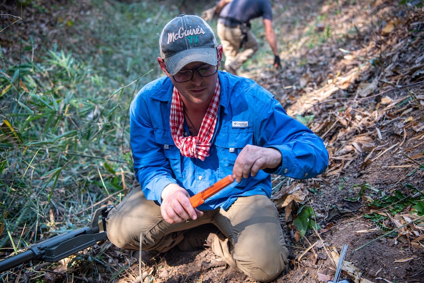 A man uses a metal detector probe.