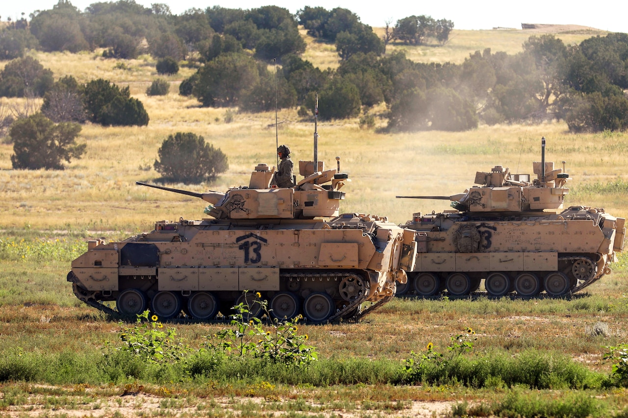 Tanks operate on a grassy field.