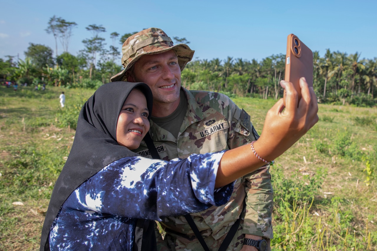 A soldier takes a selfie with a civilian.