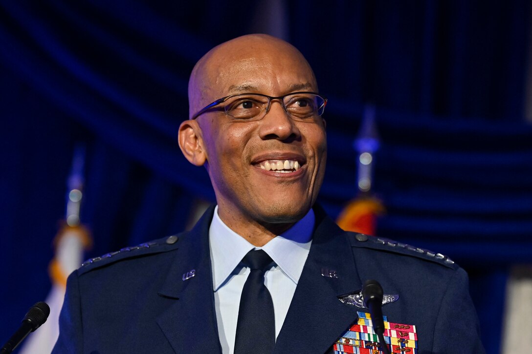 An Air Force general smiles in front of a blue curtain.