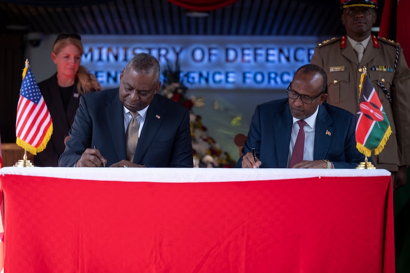 Two men sitting at a table sign papers.